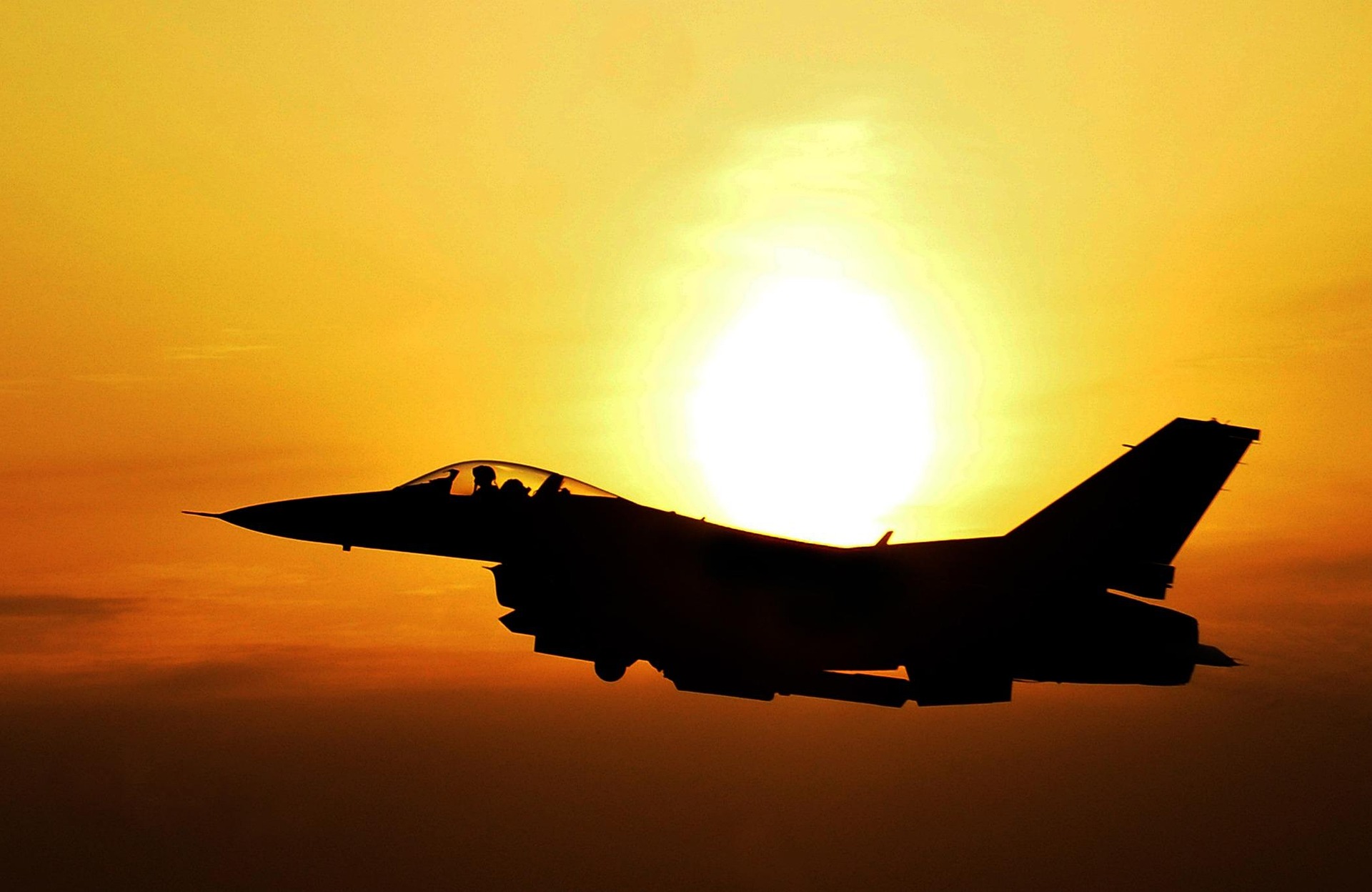 A jet plane is flying while the sun is rising.
