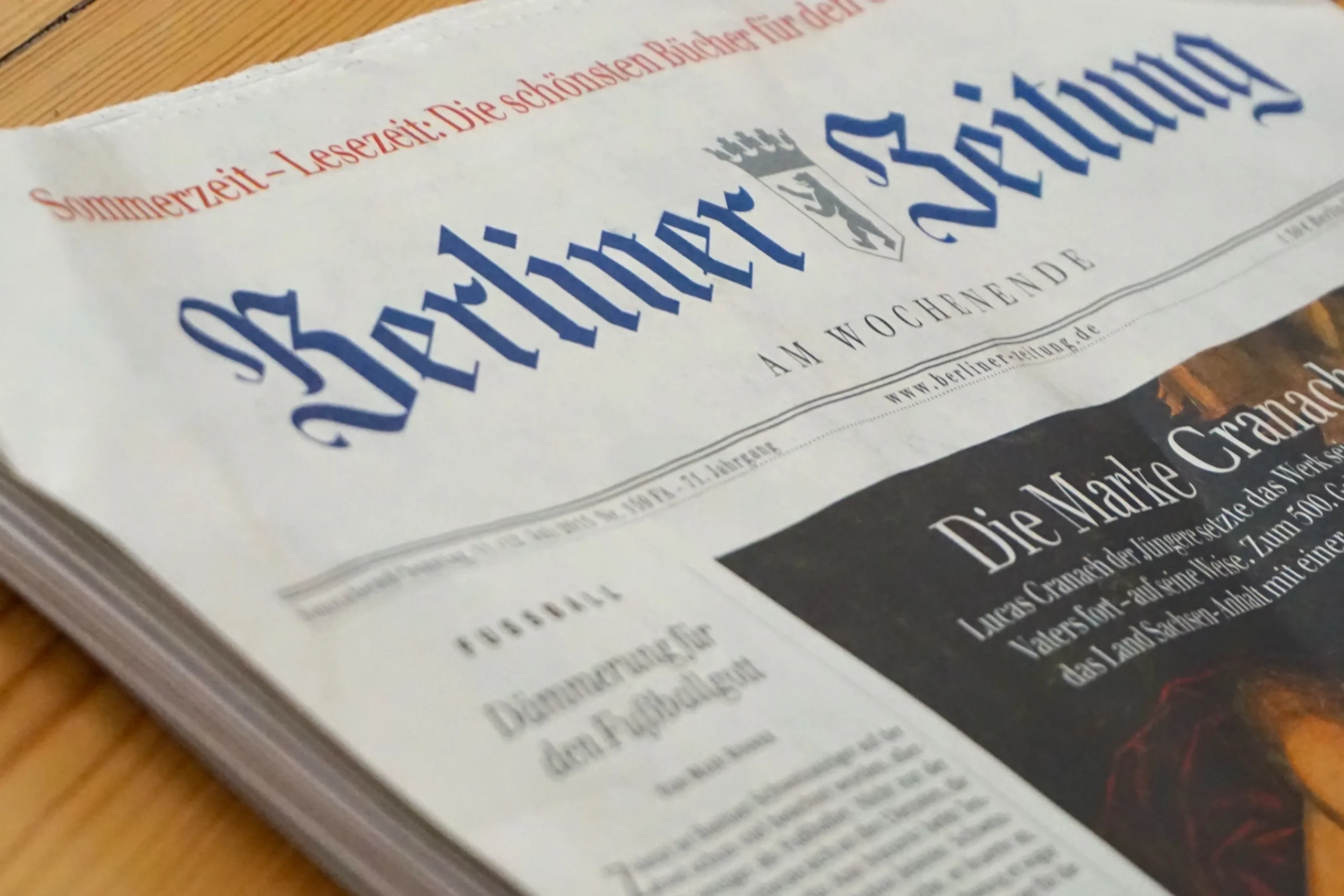 The current newspaper lying on the wooden table.