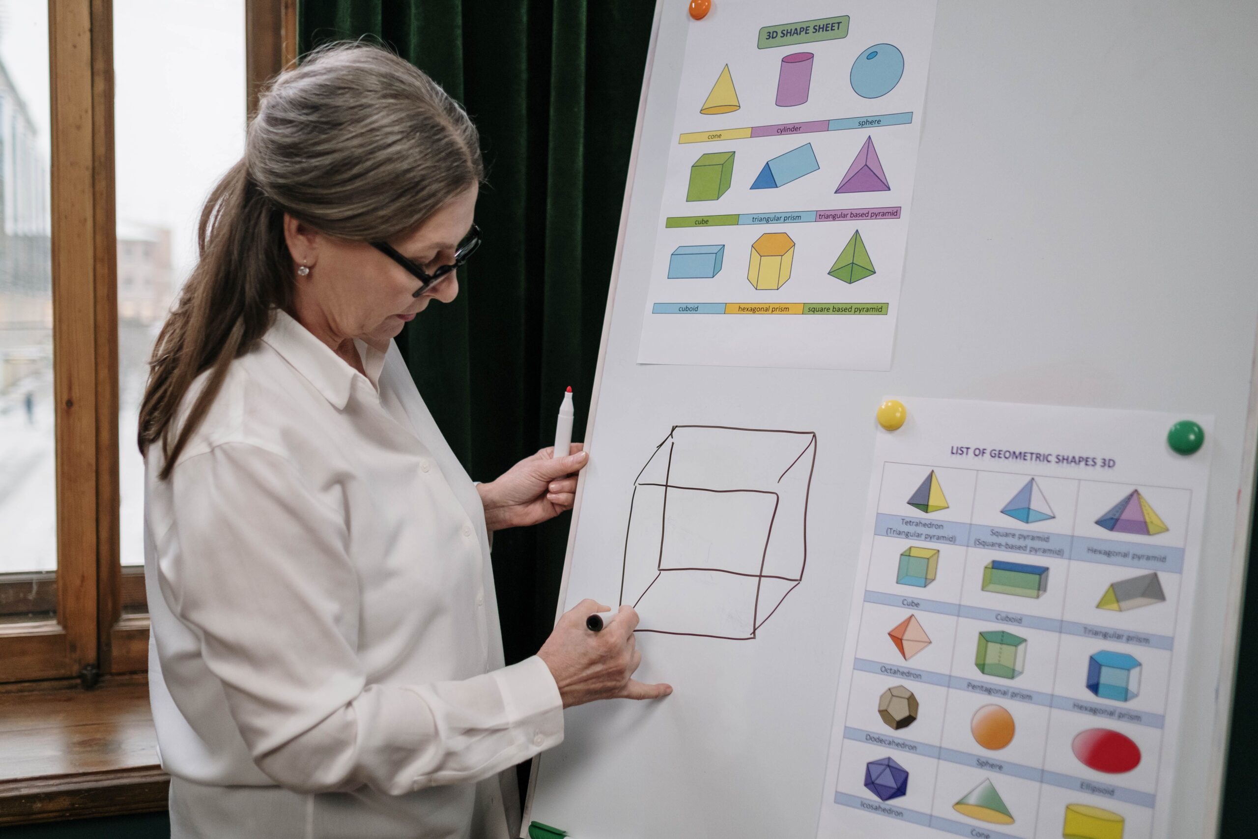 A teacher is drawing shapes on the white board.