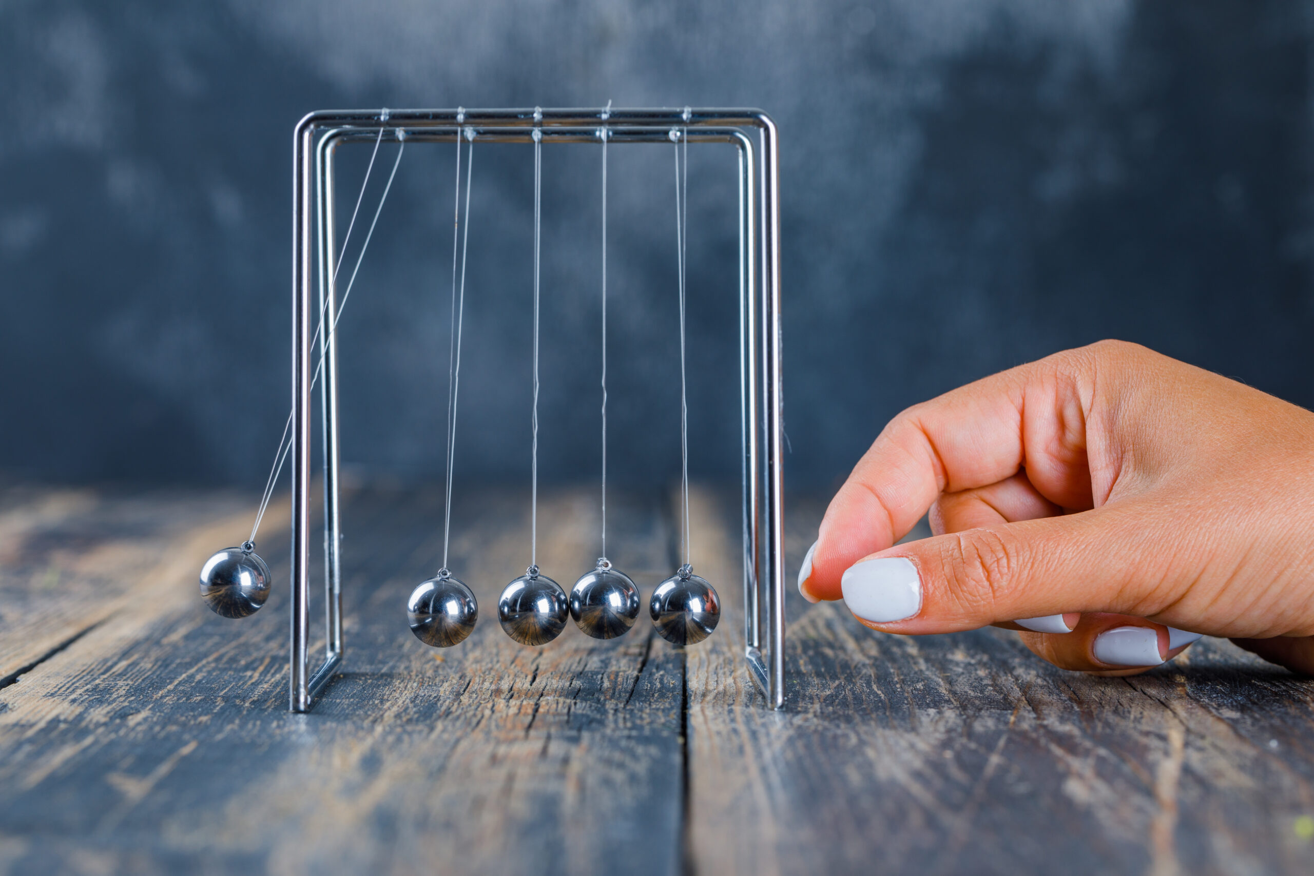 Time management concept on wooden and gloomy background side view. female working on newton's cradle.