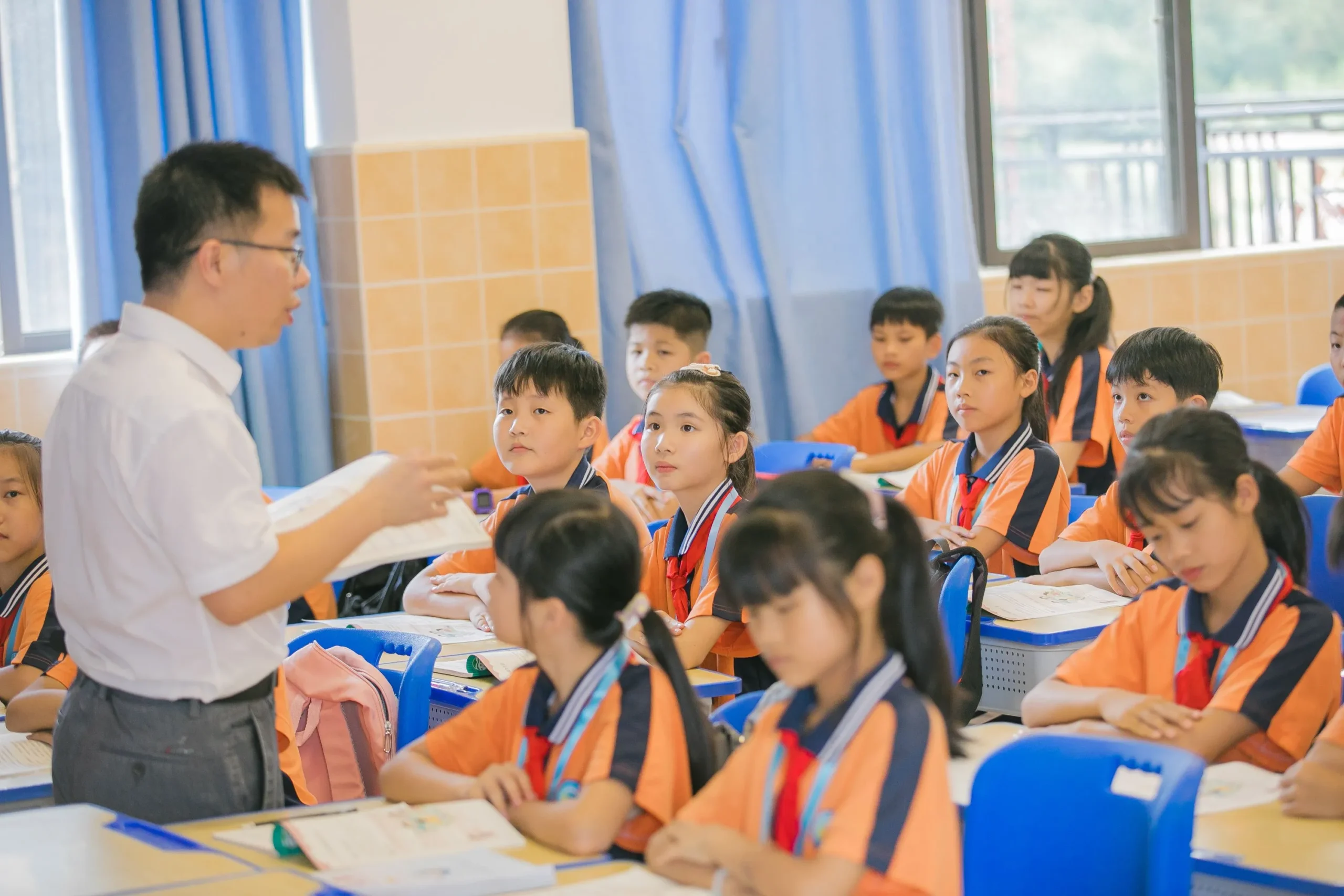 An elementary school teacher is teaching the students.