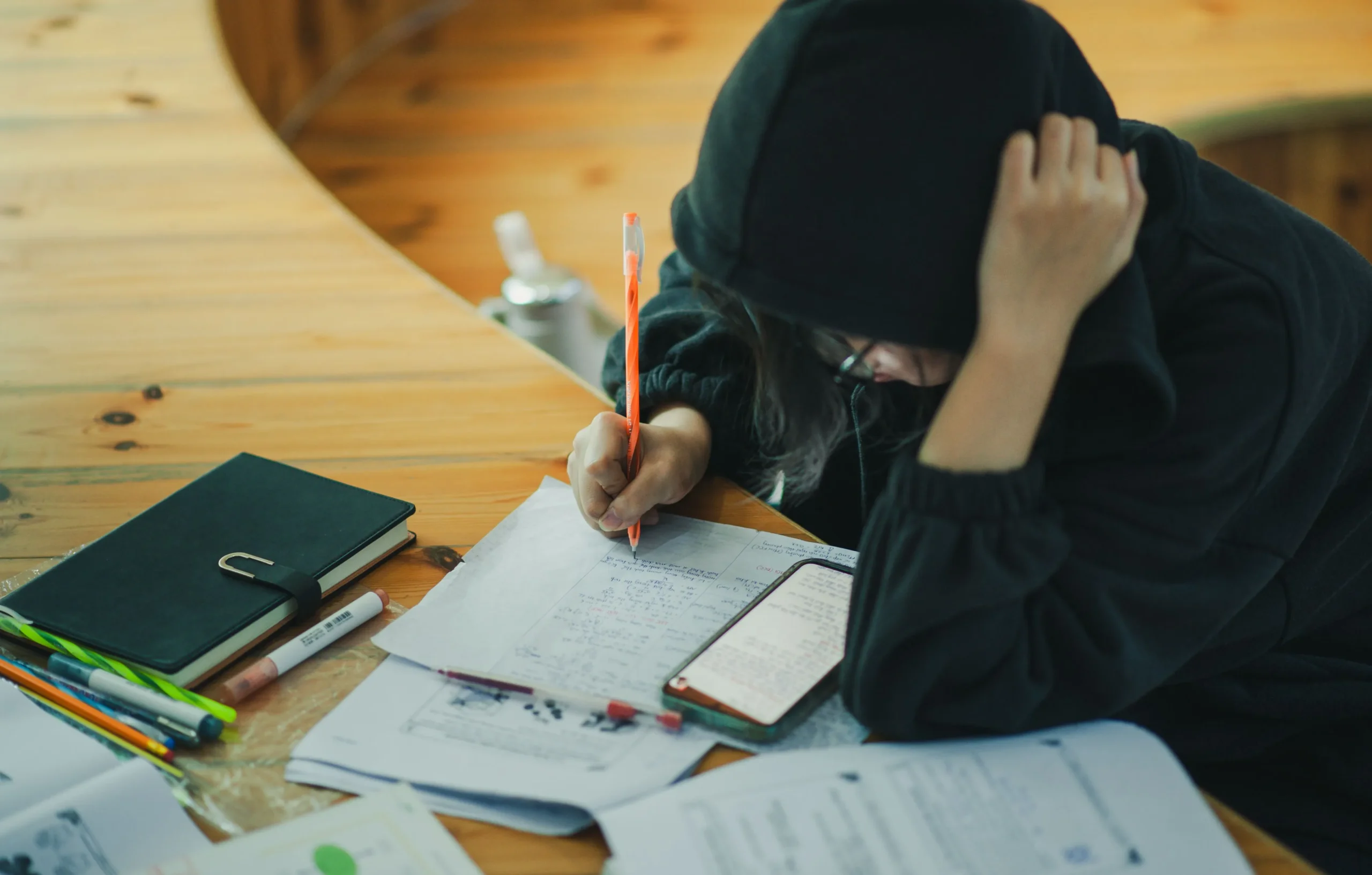A person with a hoody studying exams.